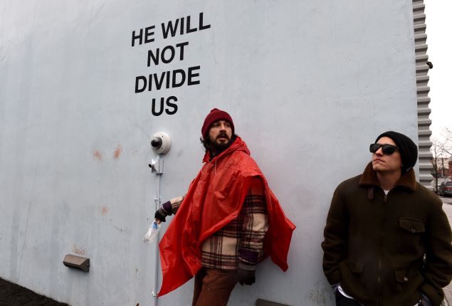 Shia LaBeouf with his performance work, He Will Not Divide Us, outside the Museum of the Moving Image in Astoria, Queens.