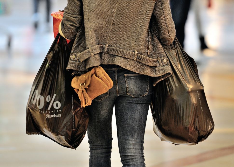 A woman carries so-called "single-use" shopping bags as she exits a shopping centre in Faches-Thumesnil, northern France, on June 27, 2014. A governmental amendment added to the biodiversity bill on June 25, aims for a total ban on single-use plastic bags.