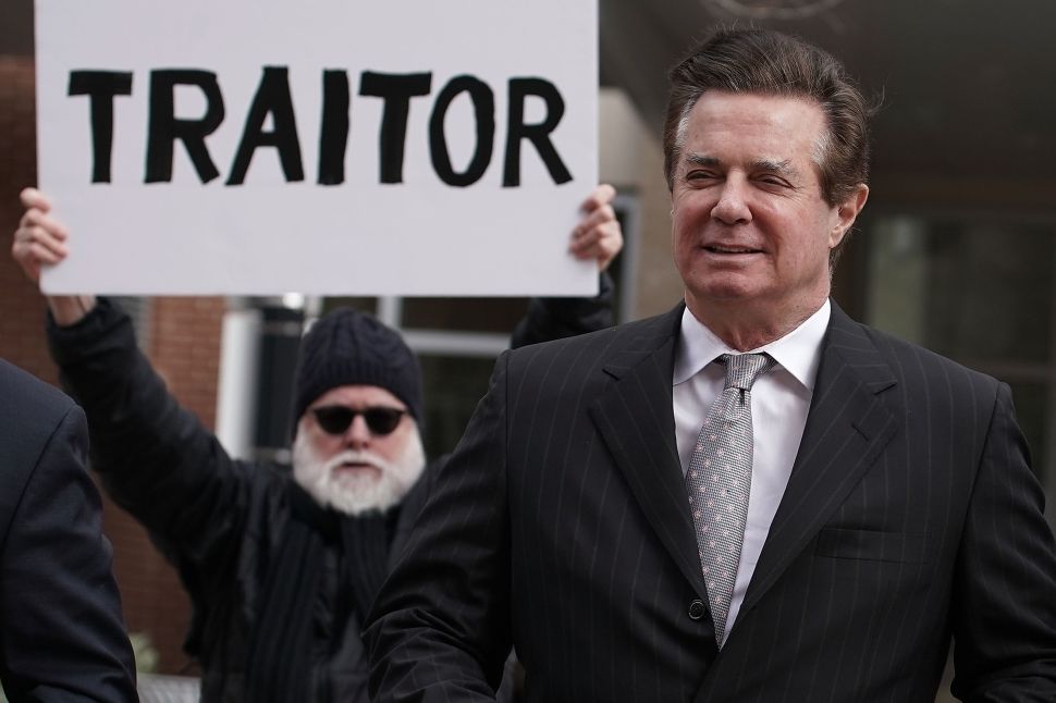 ALEXANDRIA, VA - MARCH 08: Former Trump campaign manager Paul Manafort (R) arrives at the Albert V. Bryan U.S. Courthouse for an arraignment hearing as a protester holds up a sign March 8, 2018 in Alexandria, Virginia. Manafort was scheduled to enter a plea on new tax and fraud charges, brought by special counsel Robert Mueller's Russian interference investigation team, at the Alexandria federal court in Virginia, where he resides.