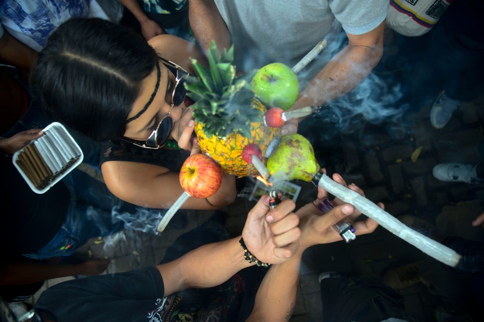 A woman smokes marijuana in a pineapple during a rally demanding its legalization.