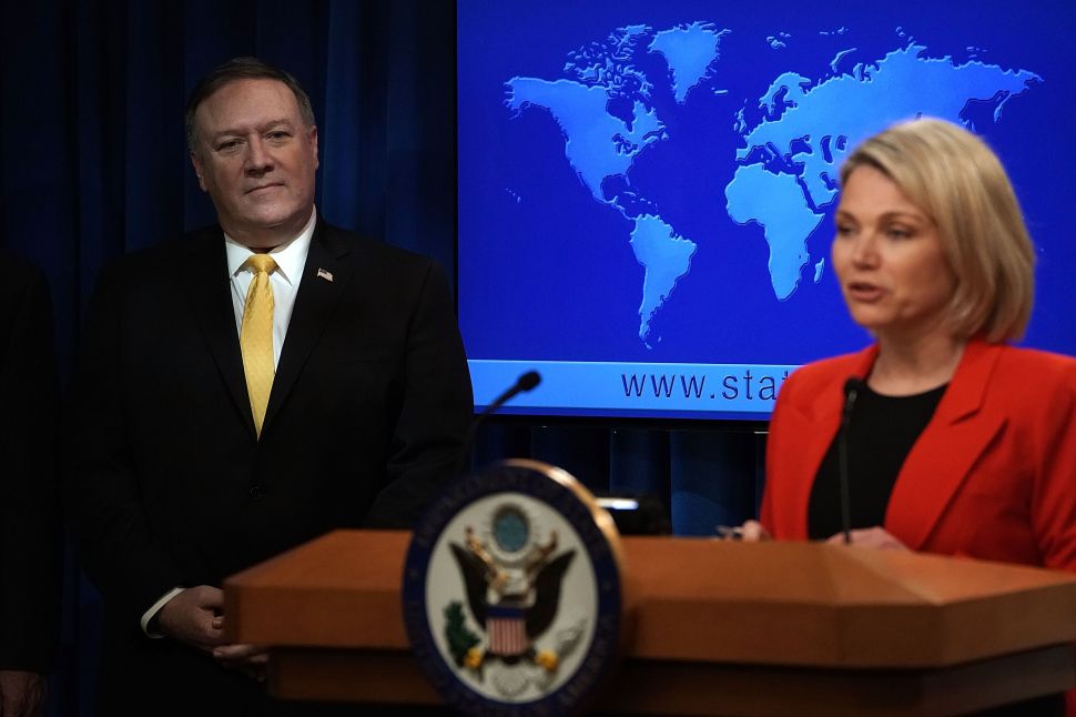 Secretary of State Mike Pompeo listens as State Department spokesperson Heather Nauert speaks during a press event.