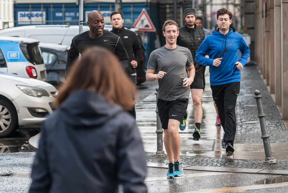 Facebook founder Mark Zuckerberg (C) runs with bodyguards in Berlin, Germany, on February 25, 2016.