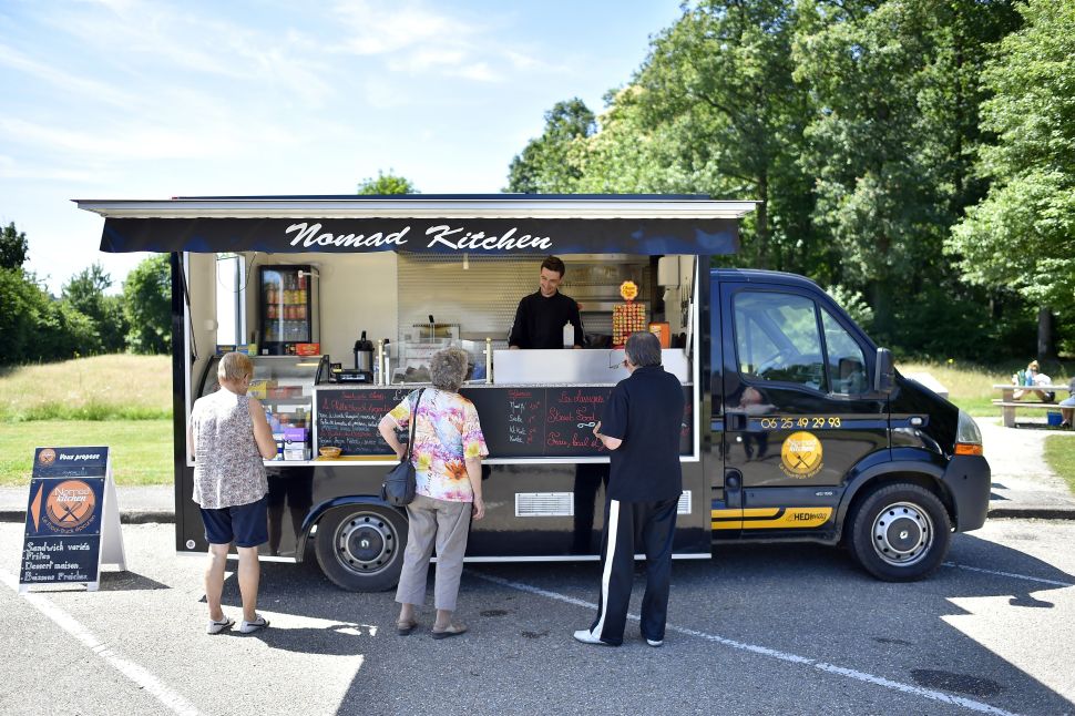 People wait to buy meals at a food truck parked on a rest area in Crevin, France.