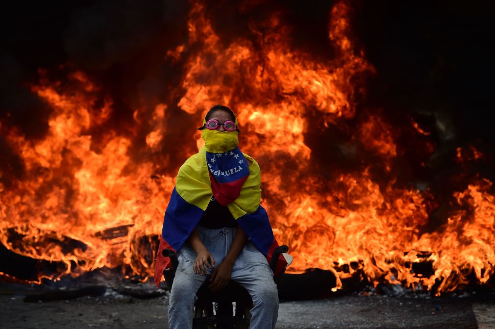 A Venezuelan opposition activist is backdropped by a burning barricade during a demonstration against President Nicolas Maduro in Caracas, on April 24, 2017.