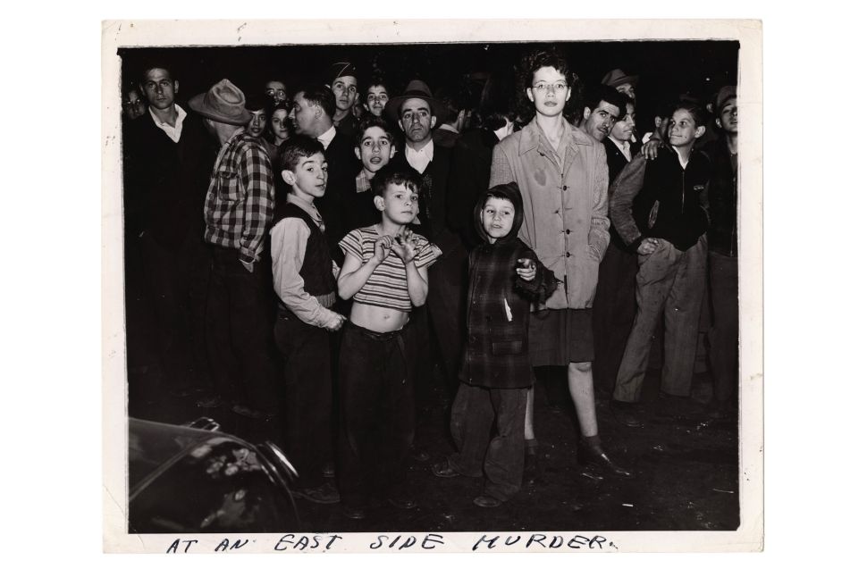 A crowd of men, women and children gathers at the scene of a murder on Manhattan's East Side, New York, circa 1940.