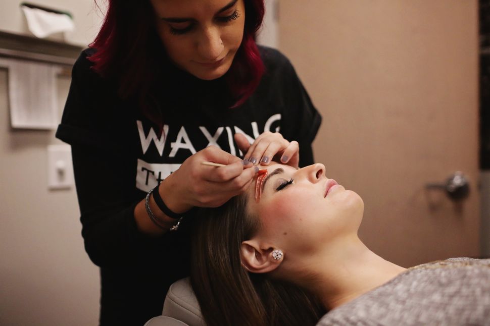 A Waxing the City "Cerologist" waxes a customer's eyebrows.