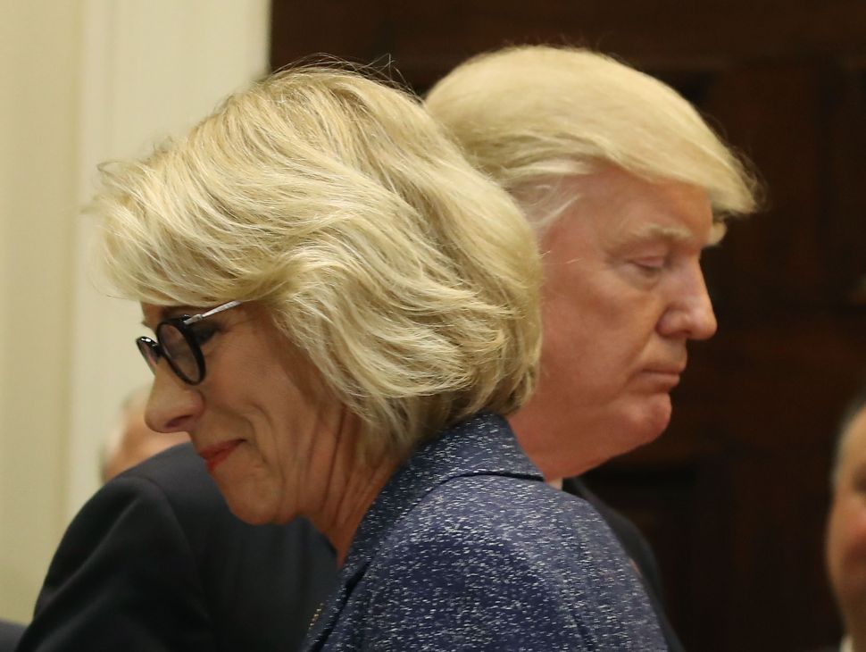 President Donald Trump stands with Education Secretary Betsy DeVos.