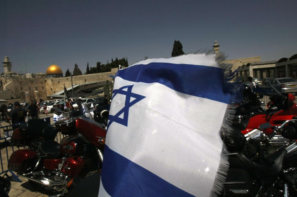 Backdropped by the Western Wall and the Dome of the Rock, an Israeli flag flutters from the back of a Harley Davidson motorcycle in Jerusalem on May 4, 2008.