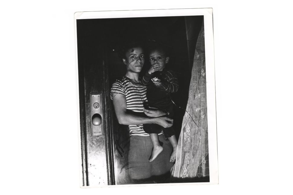 A mother holds her child in a window, Harlem, New York, New York, 1943.