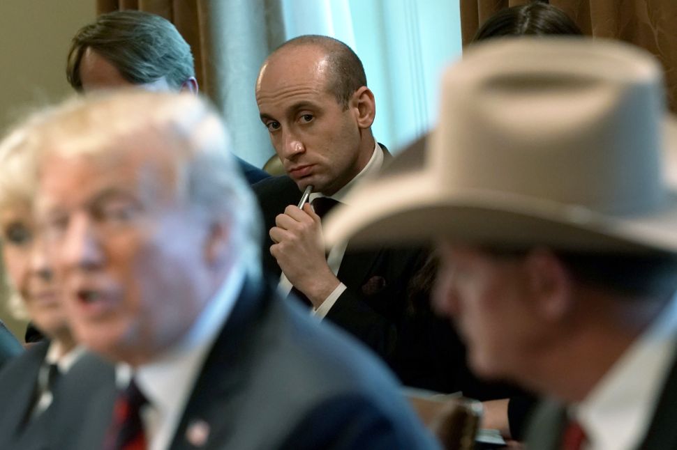 President Donald Trump speaks as Senior Advisor to the President Stephen Miller (C) listens.