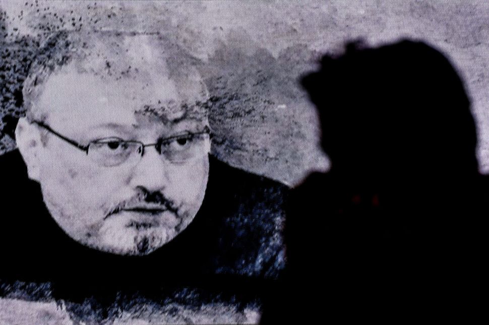 A man passes in front of a screen showing Jamal Khashoggi during a commemoration event on November 11, 2018 in Istanbul.