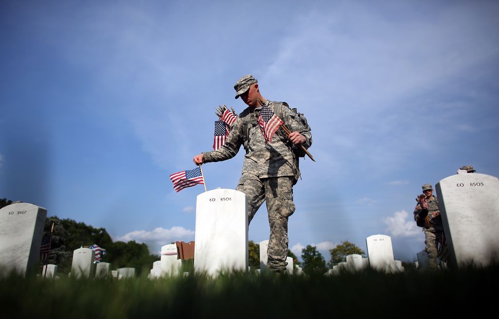 Members of the 3rd U.S. Infantry Regiment place American flags at the graves of U.S. soldiers buried in Section 60 at Arlington National Cemetery in preparation for Memorial Day.