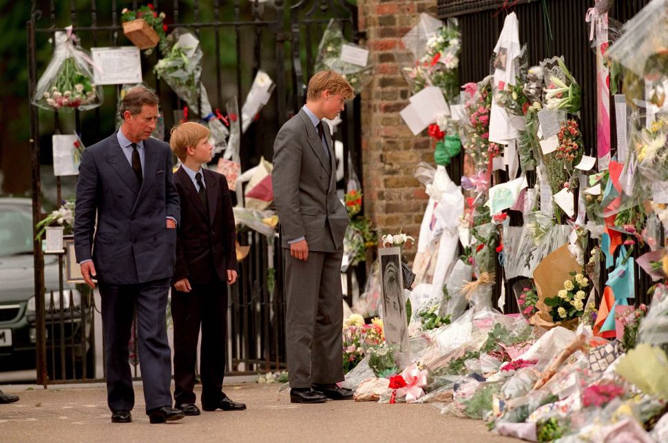 The Prince of Wales, Prince William and Prince Harry look at floral tributes to Diana, Princess of Wales, outside Kensington Palace on September 5, 1997 in London, England.