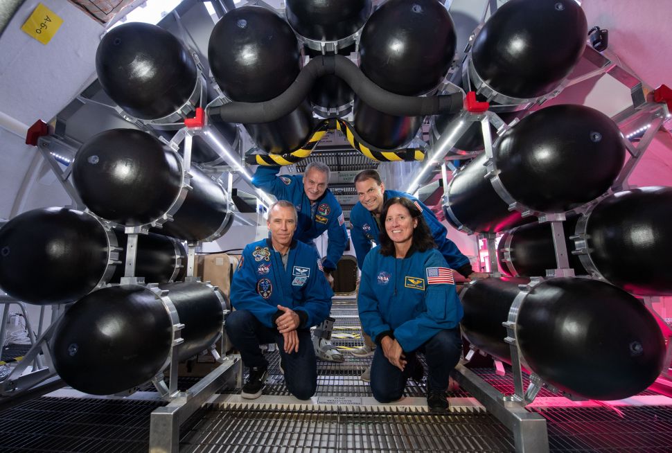 NASA astronauts participating in the B330 ground test pose next to the inflation tanks inside the Bigelow testing unit.