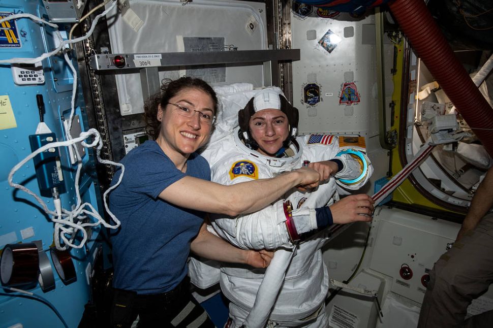 NASA astronaut Christina Koch (left) poses for a portrait with fellow Expedition 61 Flight Engineer Jessica Meir of NASA who is inside a U.S. spacesuit for a fit check.